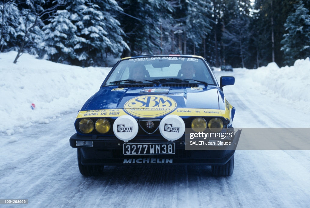 18 janvier 1984 --- Jean-Louis TRINTIGNANT prépare le rallye de Monte-Carlo avec son navigateur Boramy TIOULONG sur Alfa Roméo : l'acteur au volant de la voiture, son navigateur à ses côtés, sur une route enneigée.   (Photo by SAUER Jean-Claude/Paris Match via Getty Images)